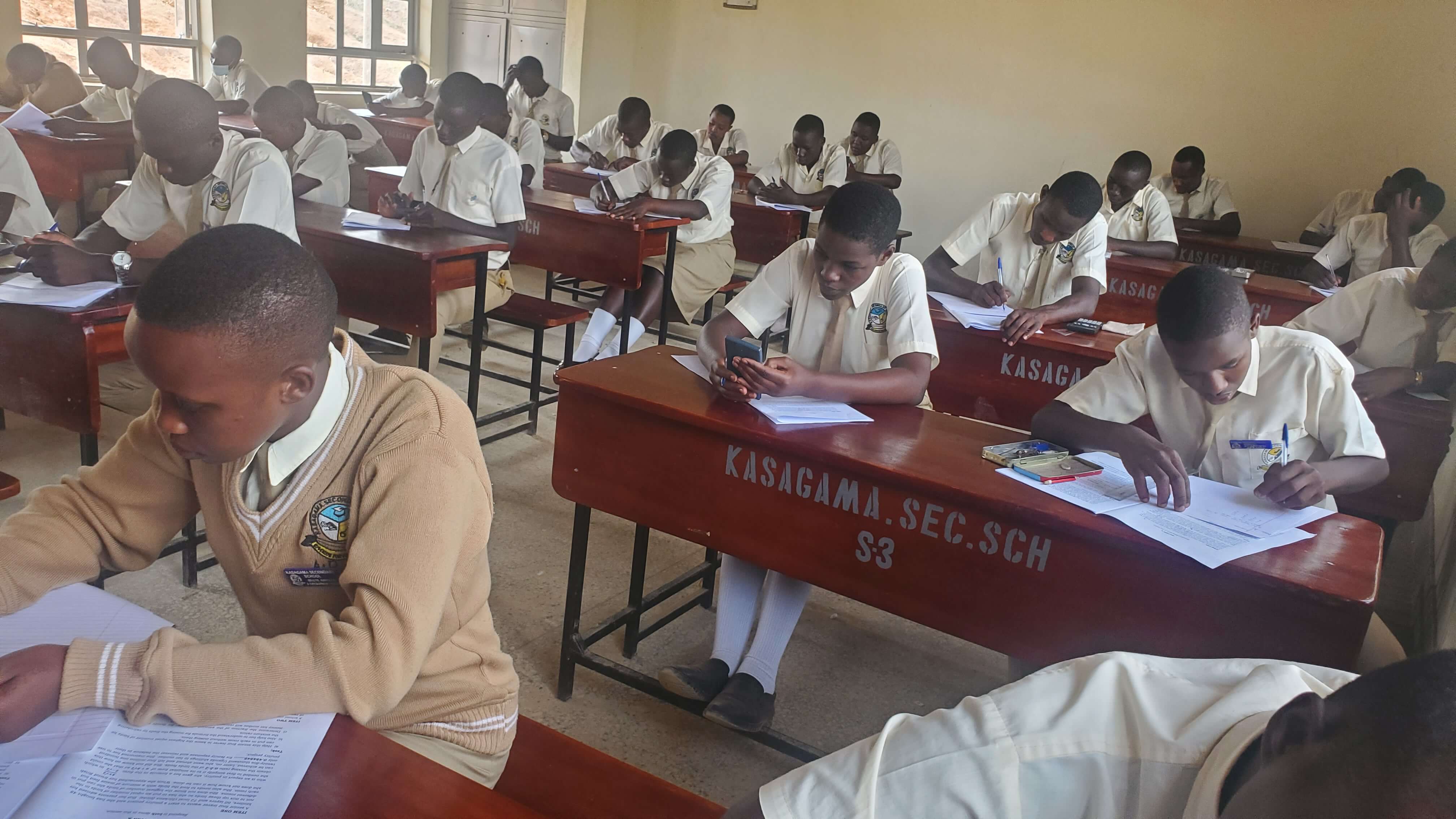 Kasagama Secondary School laboratory with students writing exams.
